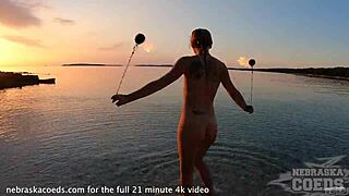 Beautiful woman dancing with fire on the beach at sunset