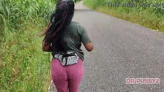 ebony with big ass in leggings runs alone in nature, showing off tattoo and prostitute vibe boldly.