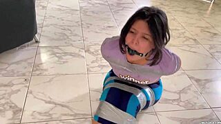 Naked girl struggles with ball gag in bondage tape