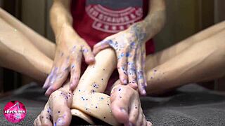 Girl plays with glitters while giving a wild footjob to dildo.